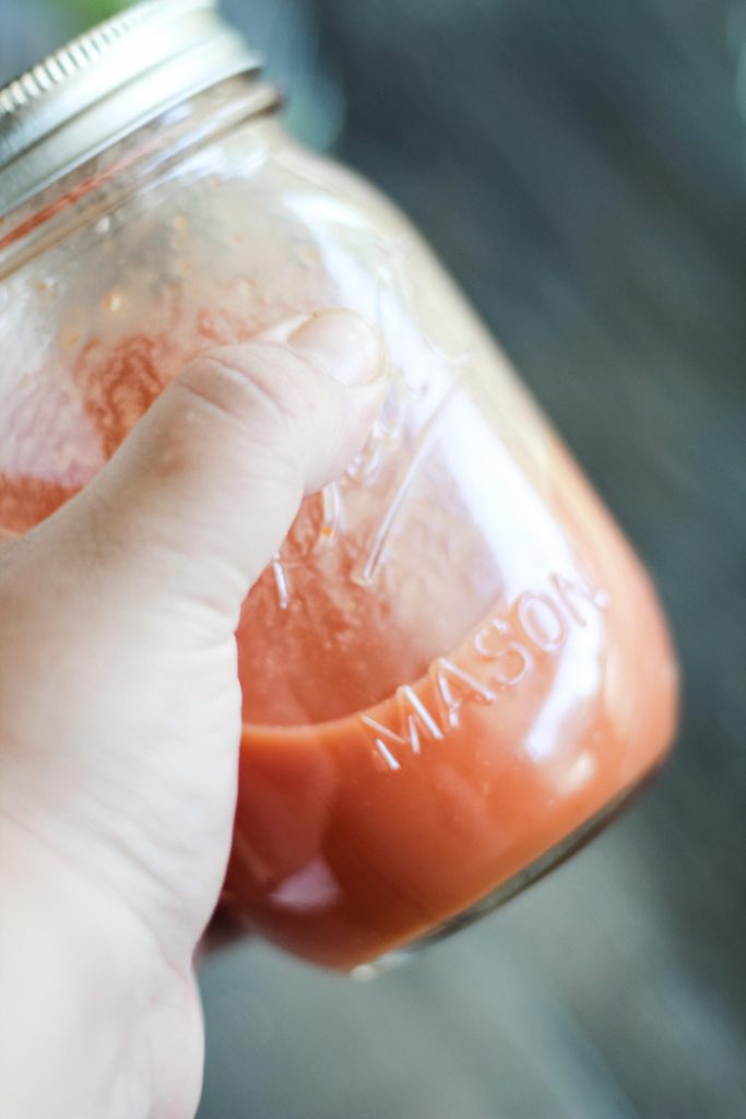 bloody mary cocktail being shaken together in a glass mason jar