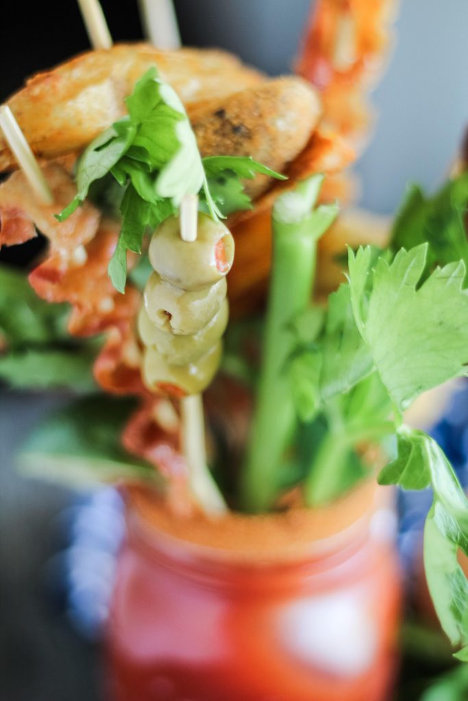 ultimate bloody mary in a Mason jar with a variety of skewered appetizers for garnish