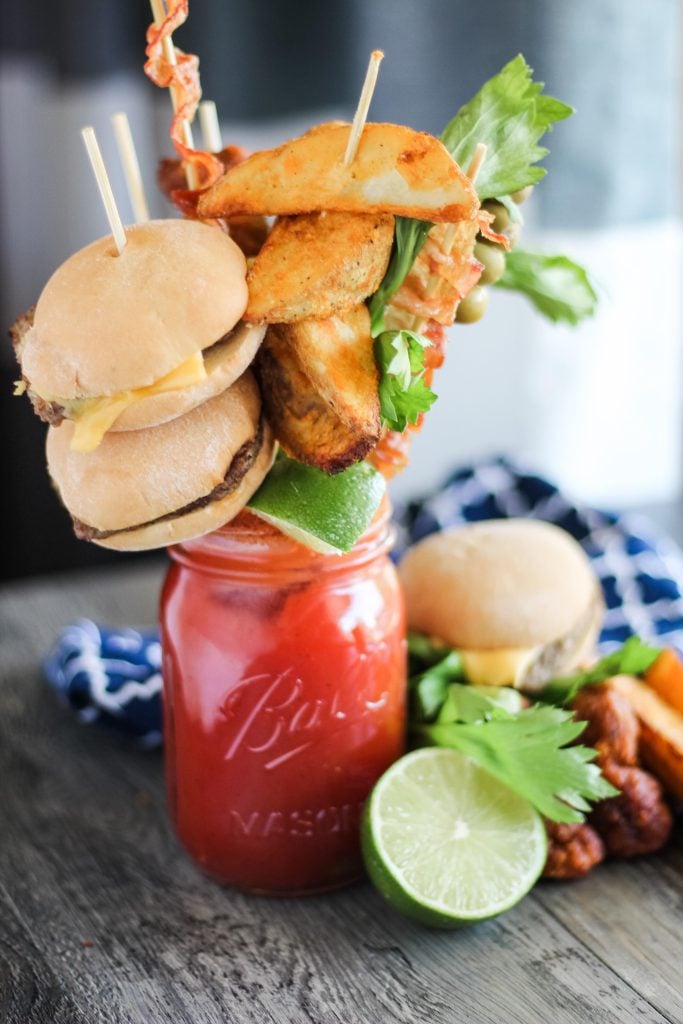 ultimate bloody mary in a Mason jar with a variety of skewered appetizers for garnish