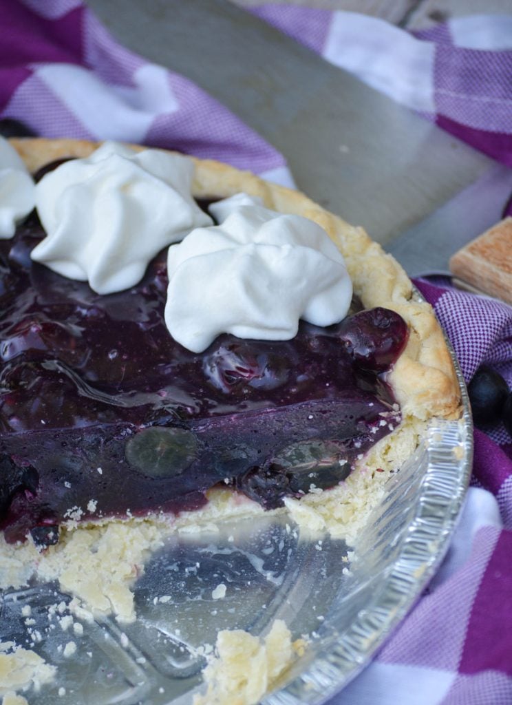 grape jello pie shown in an aluminum pie tin topped with dollops of whipped cream