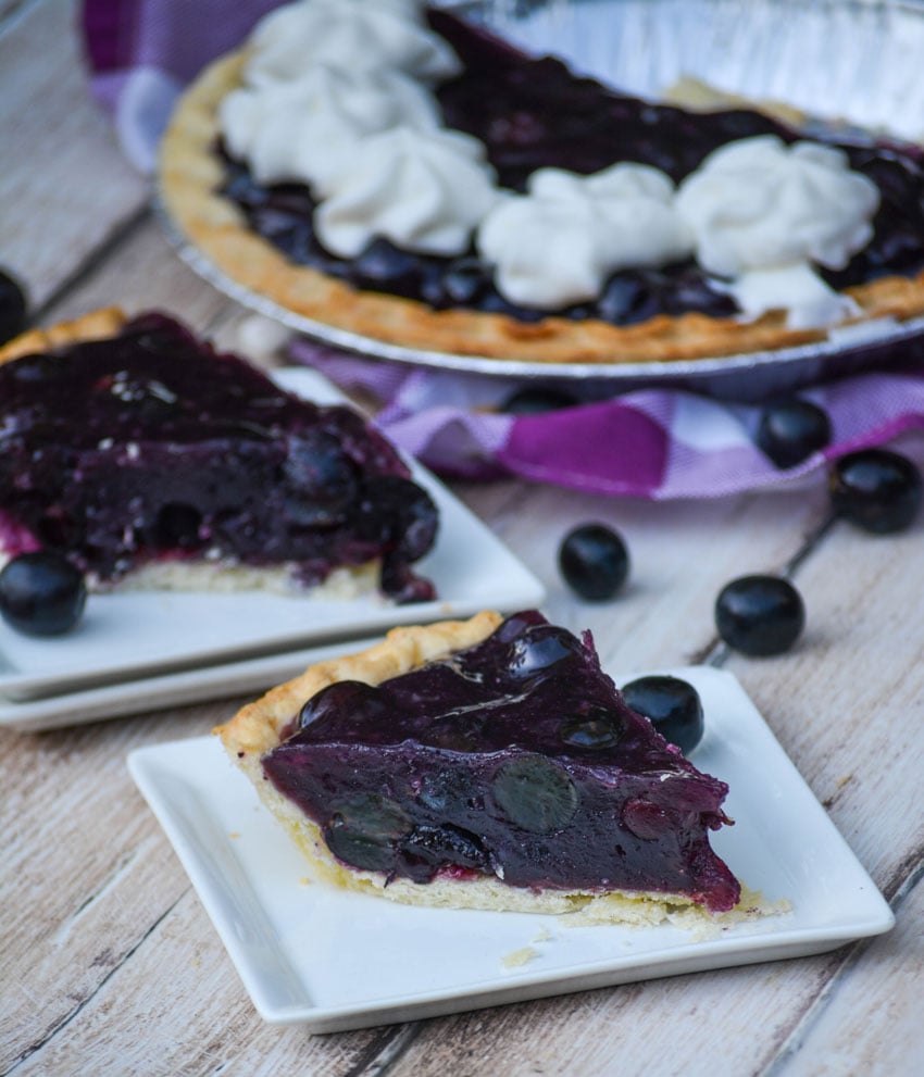 slices of black grape jello pie shown on square white appetizer plates