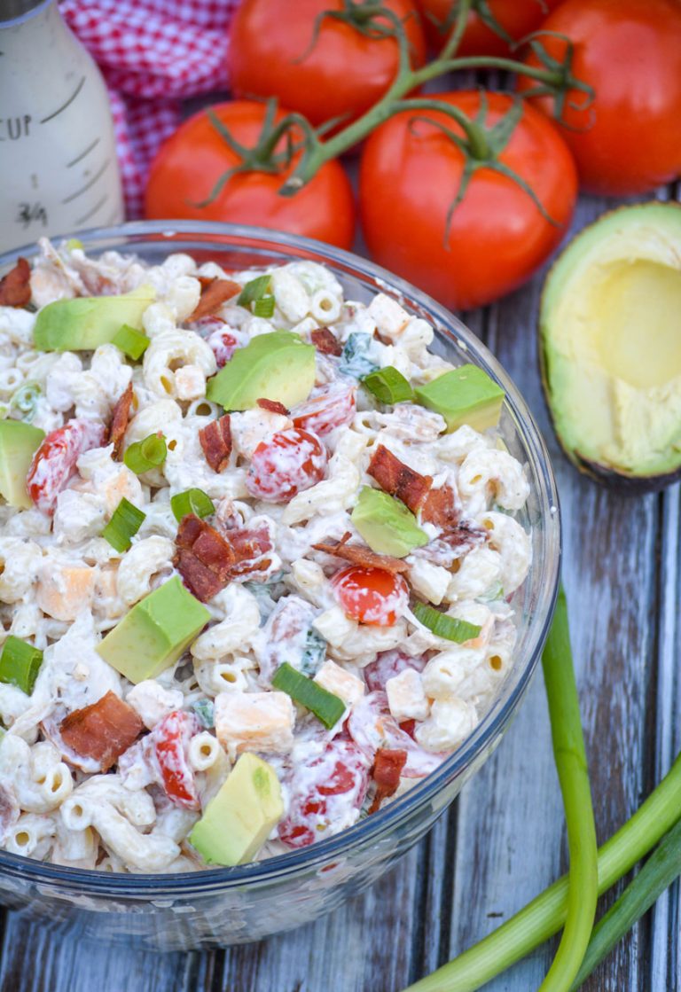 chicken club pasta salad in a glass mixing bowl surrounded by fresh produce