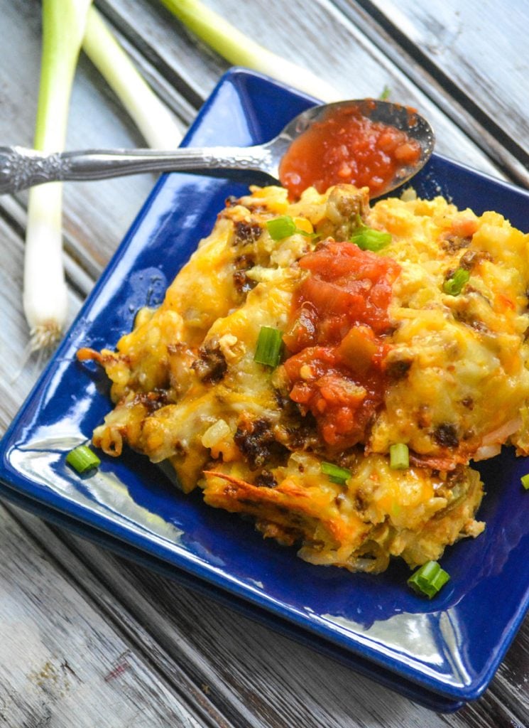 chile relleno casserole with chorizo shown on a blue square plate with a spoonful of picante sauce on the side