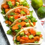 chili lime fish stick tacos in flour tortillas shown in a row on a white rectangular serving platter