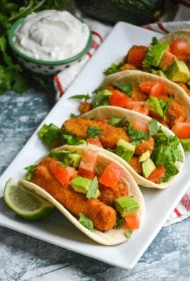 chili lime fish stick tacos in flour tortillas shown in a row on a white rectangular serving platter
