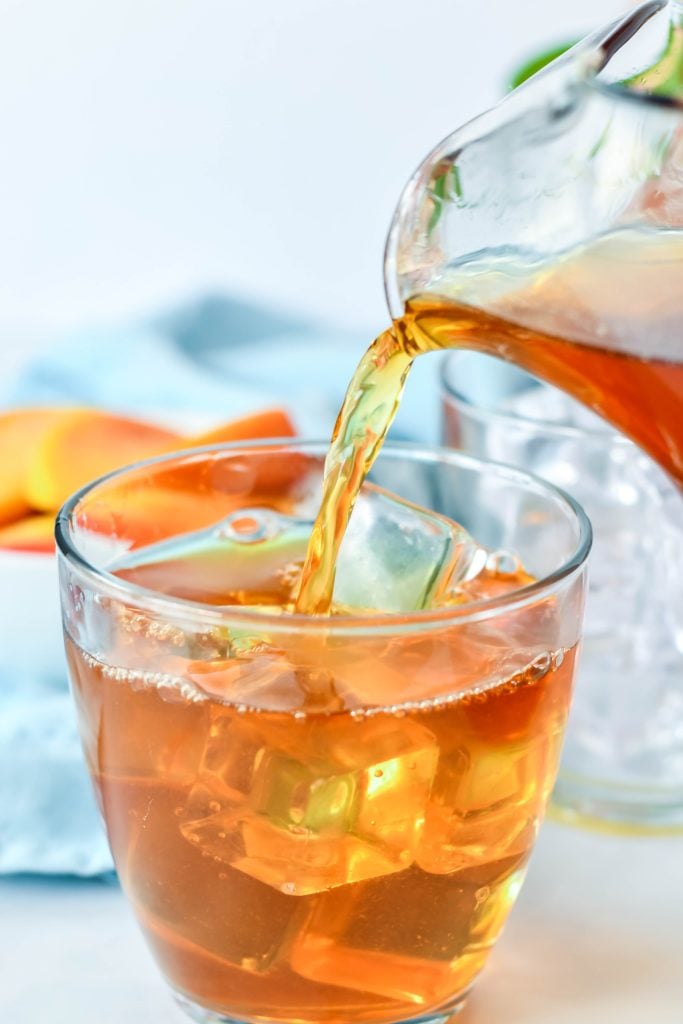 Southern sweet peach tea being poured over ice into a clear glass