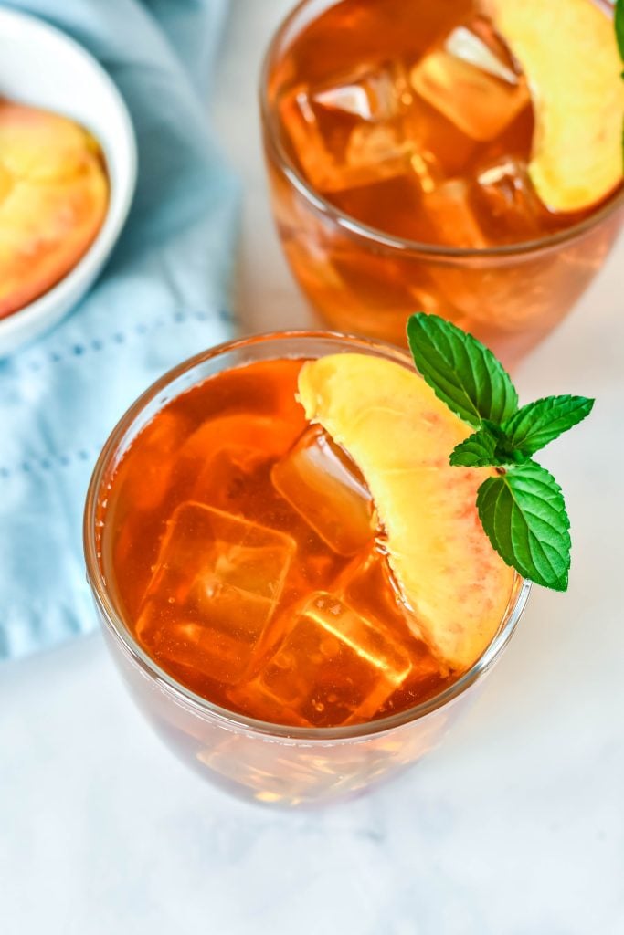 Southern sweet Peach Tea Recipe served in clear glasses and garnished with fresh peach slices and a sprig of mint
