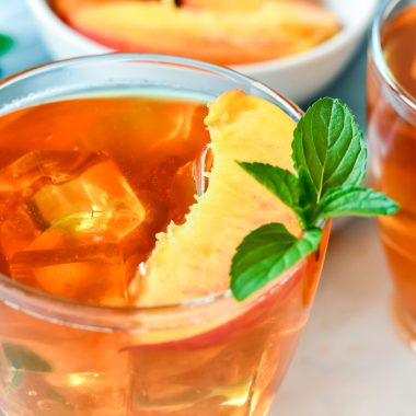 Peach Tea Recipe served in clear glasses and garnished with fresh peach slices and a sprig of mint