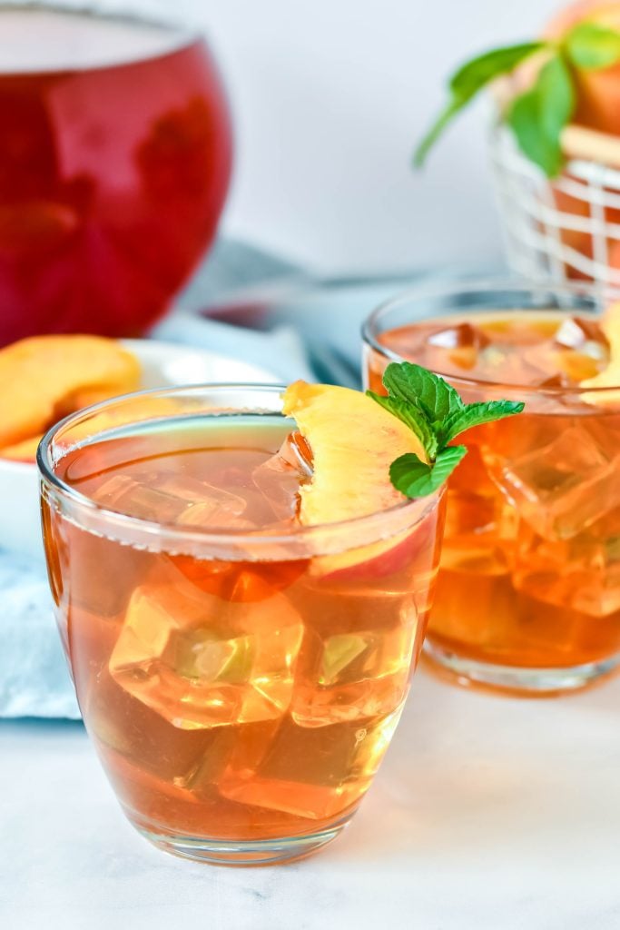 sweet Peach Tea Recipe served in clear glasses and garnished with fresh peach slices and a sprig of mint