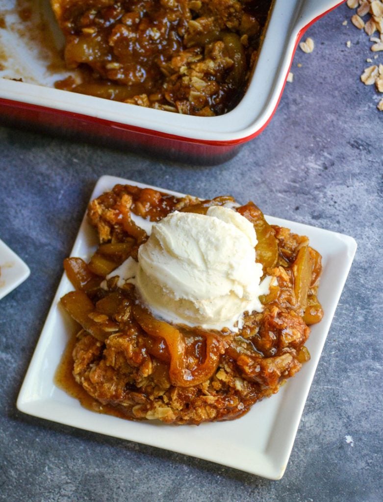 mock apple crisp served on a white square appetizer plate and topped with a melting scoop of vanilla ice cream