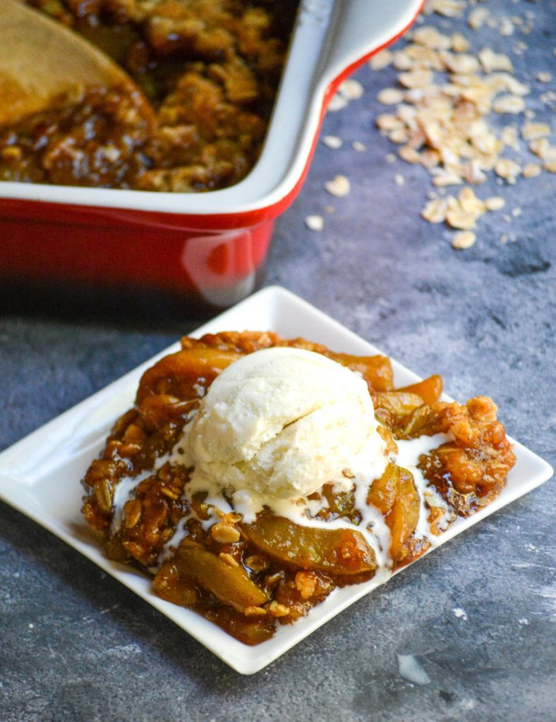 mock apple crisp served on a white square appetizer plate and topped with a melting scoop of vanilla ice cream