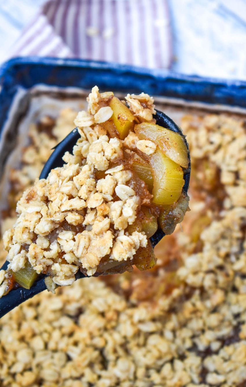 a wooden handled spoon holding up a scoop of mock apple crisp