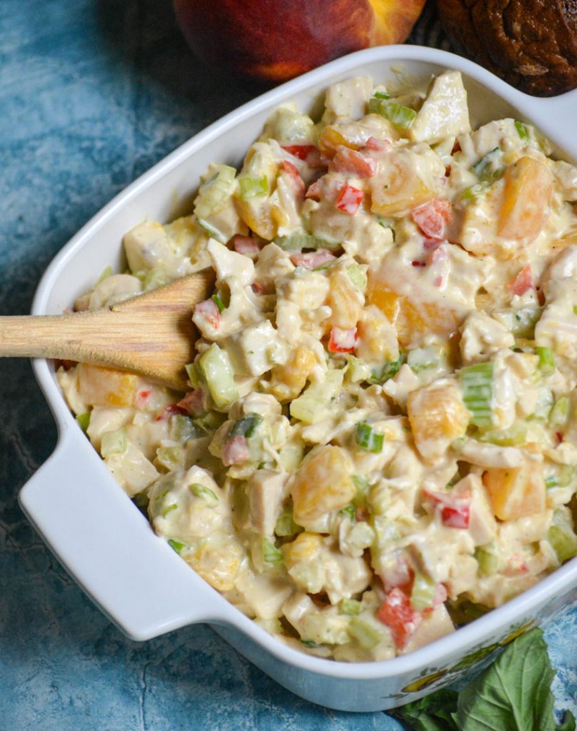 peach basil chicken salad in a white square pyrex dish with a wooden spoon