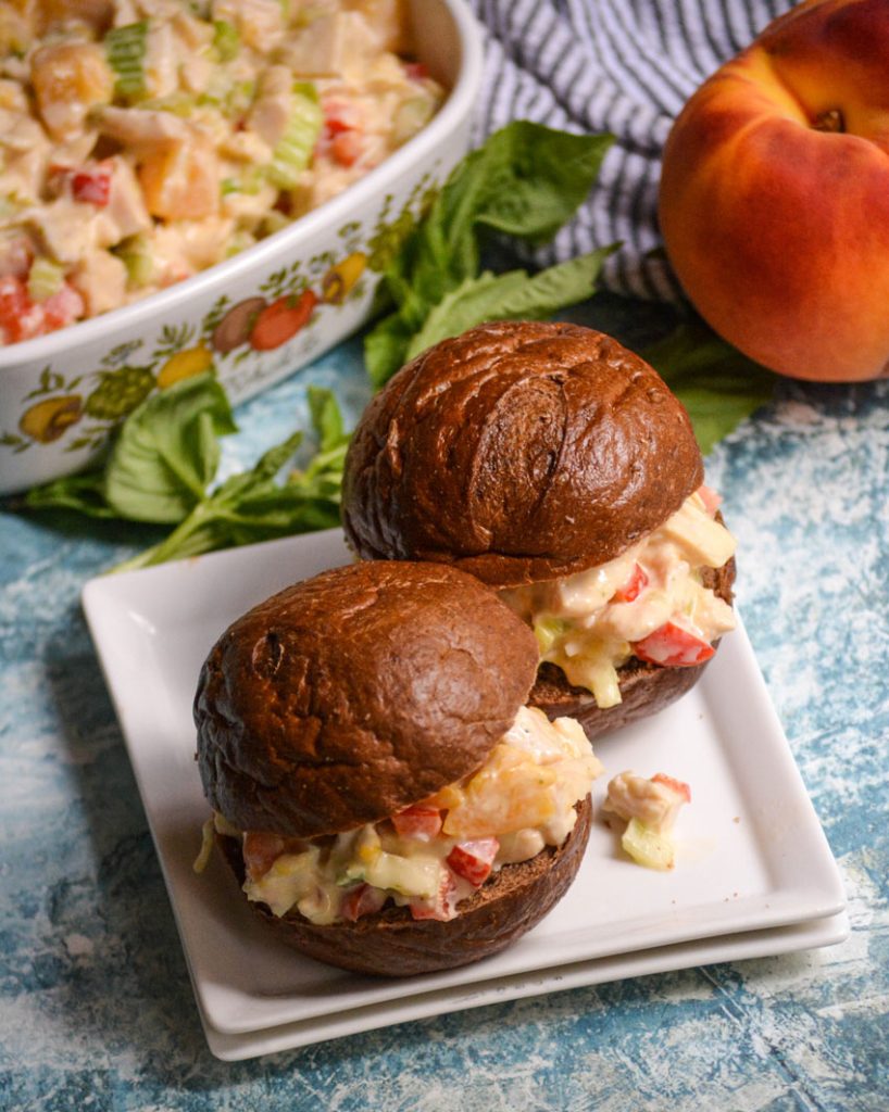 peach basil chicken salad shown on pumpernickel slider buns on a white appetizer plate