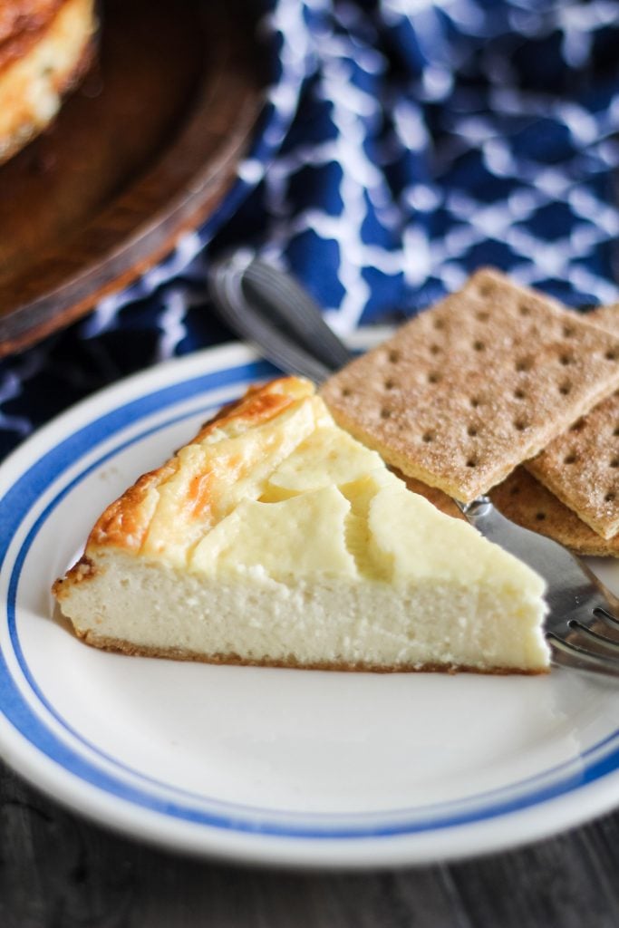 a slice of new york style cheesecake on a blue rimmed white plate 