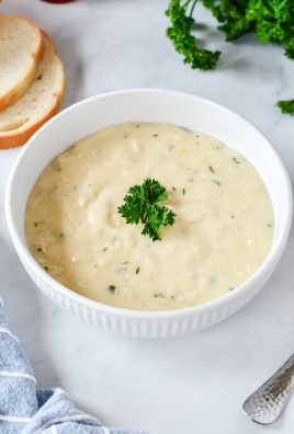 condensed cream of chicken soup shown in a white soup bowl, and topped with a sprig of fresh parsley