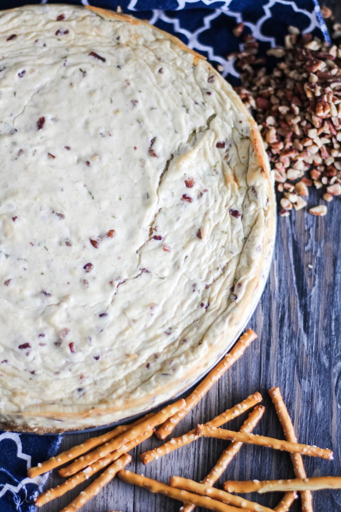 a savory cheesecake with pretzel sticks and chopped pecans strewn about the background