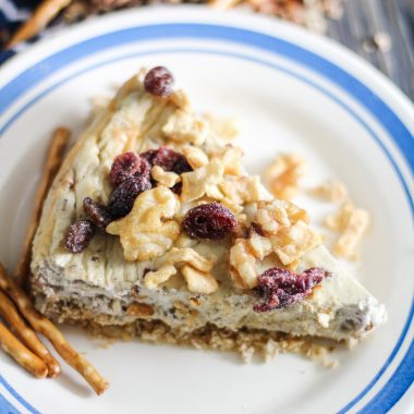 savory cheesecake served on a white plate and topped with chopped pecans and dried cranberries