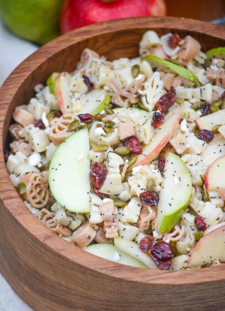 fall harvest pasta salad in a large wooden bowl with fresh apples in the background