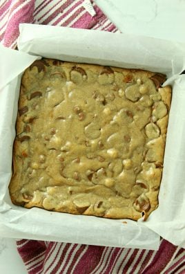 baked rolo chocolate chip blondies shown in a parchment paper lined baking dish