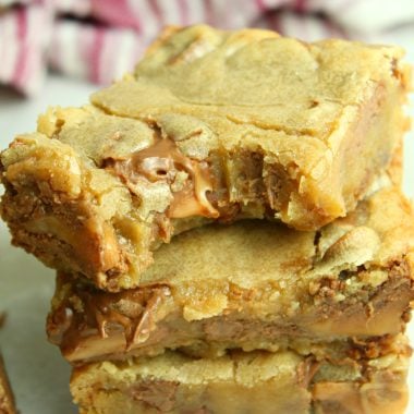 rolo chocolate chip blondie bars stacked three high with a bite clearly taken out of the top square showing the gooey caramel inside