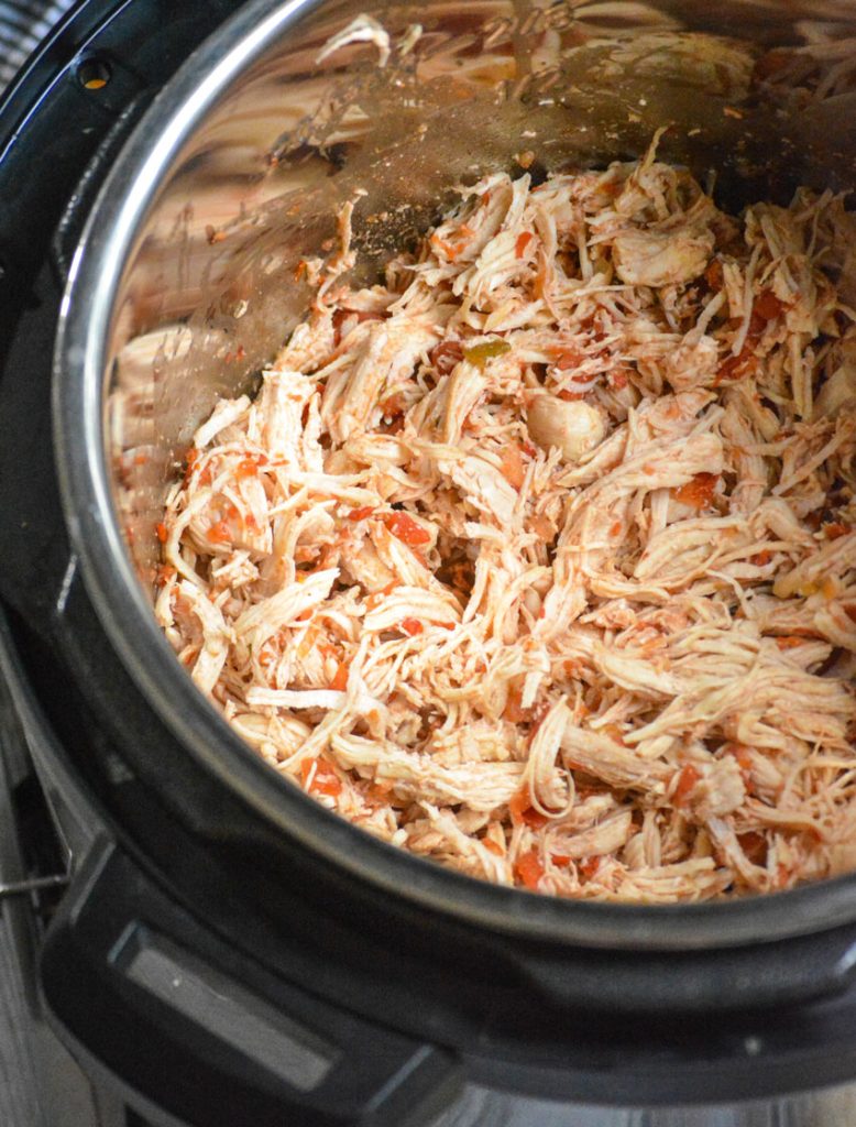 instant pot salsa chicken shown shredded in the silver bowl of an Instant Pot pressure cooker