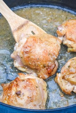 a wooden spoon holding up a pan fried chicken thigh that's been coated in apple cider gravy