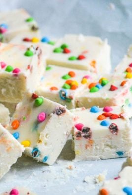 a pile of chunks of rainbow chip frosting, two ingredient fudge shown on a crinkled piece of white parchment paper