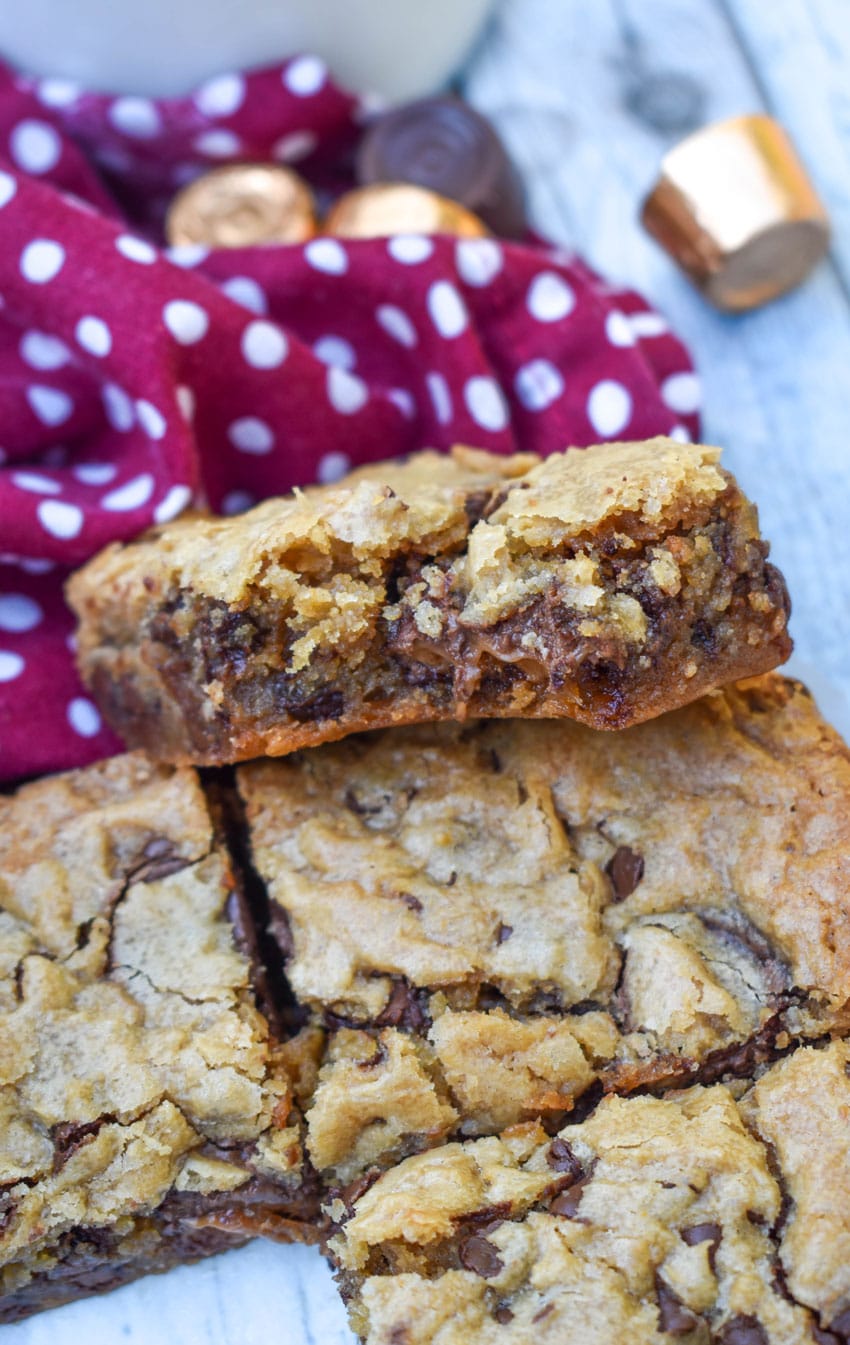 squares of rolo chocolate chip blondies stacked on a wooden table