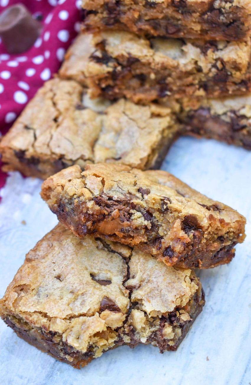 two squares of rolo chocolate chip blondies stacked on a wooden table