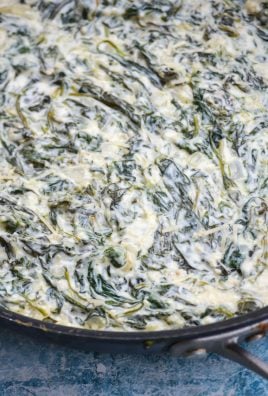 a close up of cheesy creamed spinach in a large black skillet