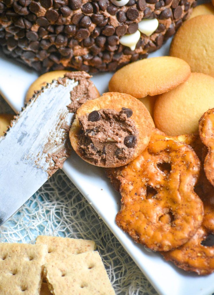 death by chocolate cheese ball shown spread on a vanilla wafer cookie with spread off to the side and cookies and crackers in the background