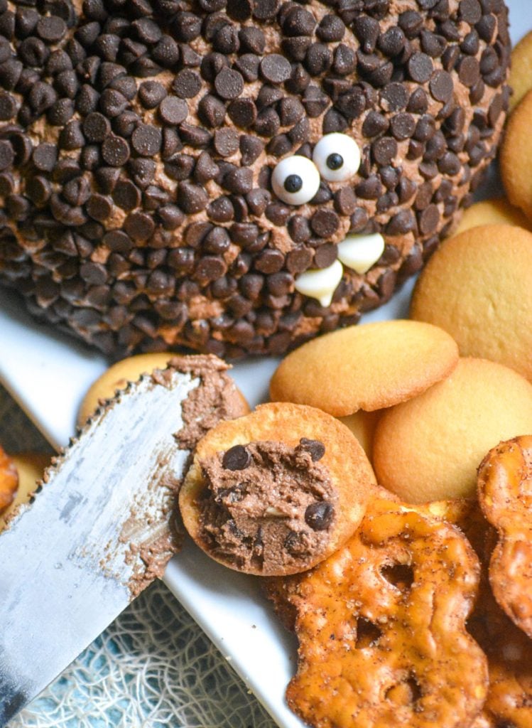 death by chocolate cheese ball shown spread on a vanilla wafer cookie with spread off to the side and cookies and crackers in the background
