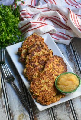 crispy mashed potato & stuffing pancakes shown on a white platter with a small bowl of applesauce on the side