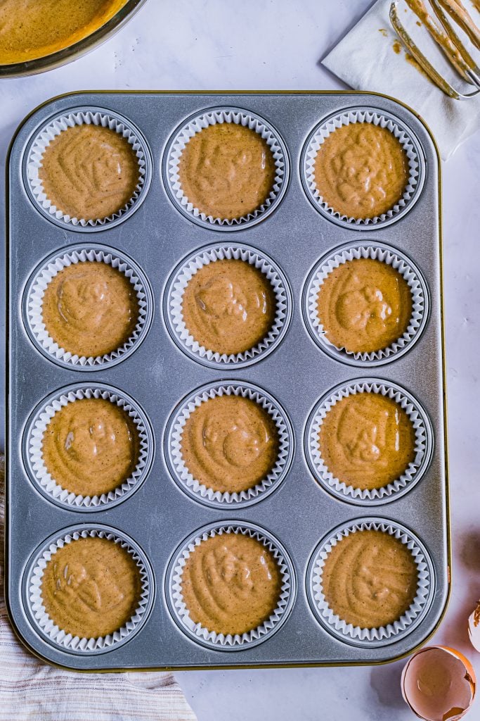 gingerbread cupcake batter shown poured into white paper lined muffin tins