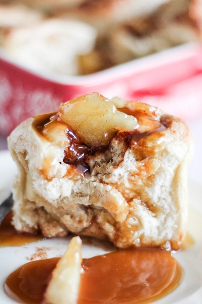 a caramel apple cinnamon rolls served on a white plate and drizzled with extra caramel sauce