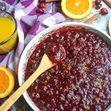 Instant pot cranberry sauce shown in a large shallow white serving dish with a wooden spoon for serving