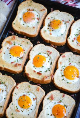 sheet pan egg in a hole shown on a dark brown sheet pan with a cloth napkin, cut out bread holes, and a bunch of green onions in the background