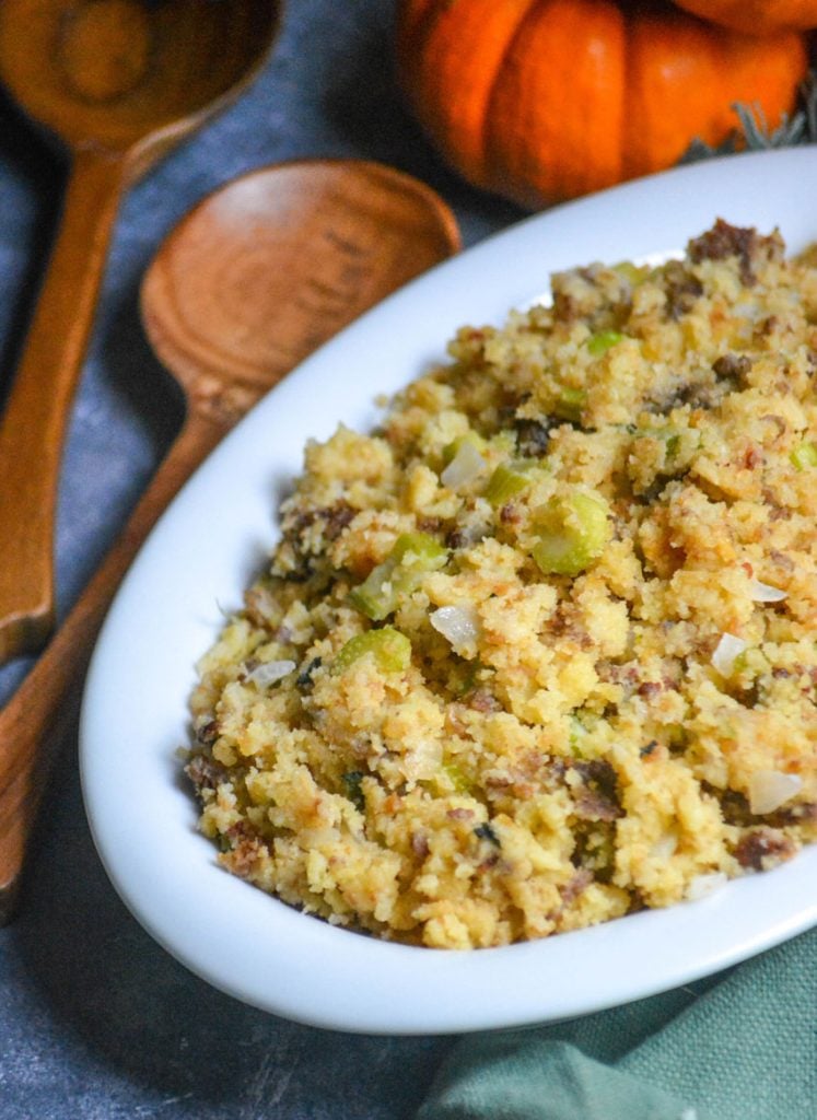 slow cooker cornbread sausage stuffing served in a white oval platter with a wooden spoon on the side