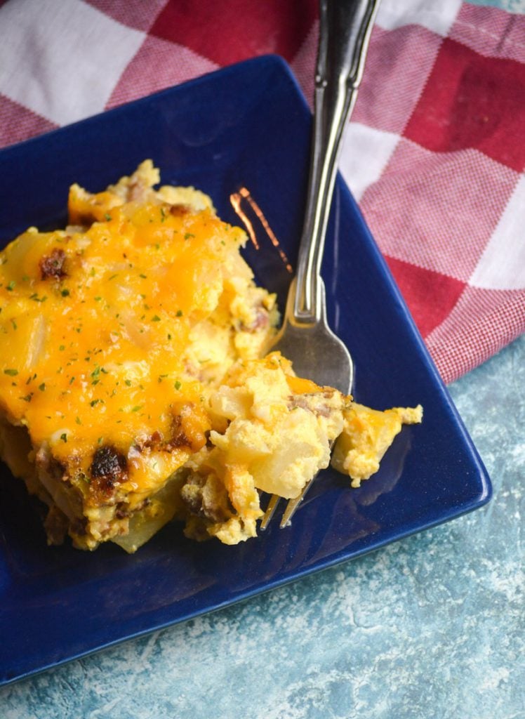 a silver fork digging into a slice of Amish breakfast casserole, shown on a blue plate