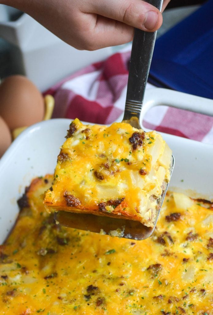 a silver spatula holding up a a slice of Amish breakfast casserole