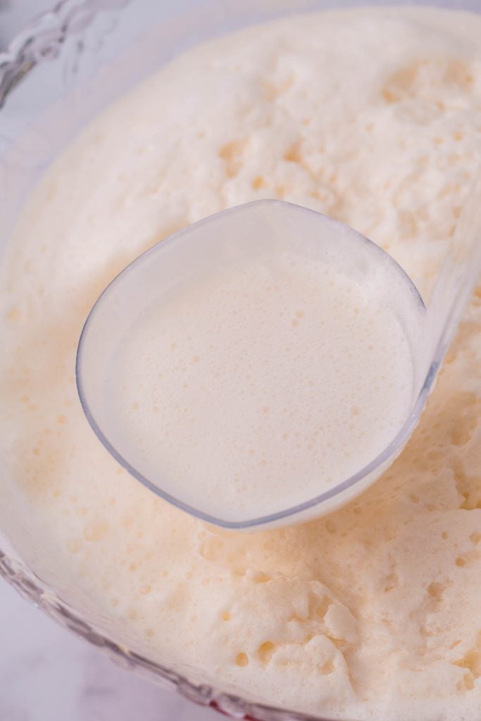 a ladle spooning a scoop of creamy white christmas punch from a glass punch bowl