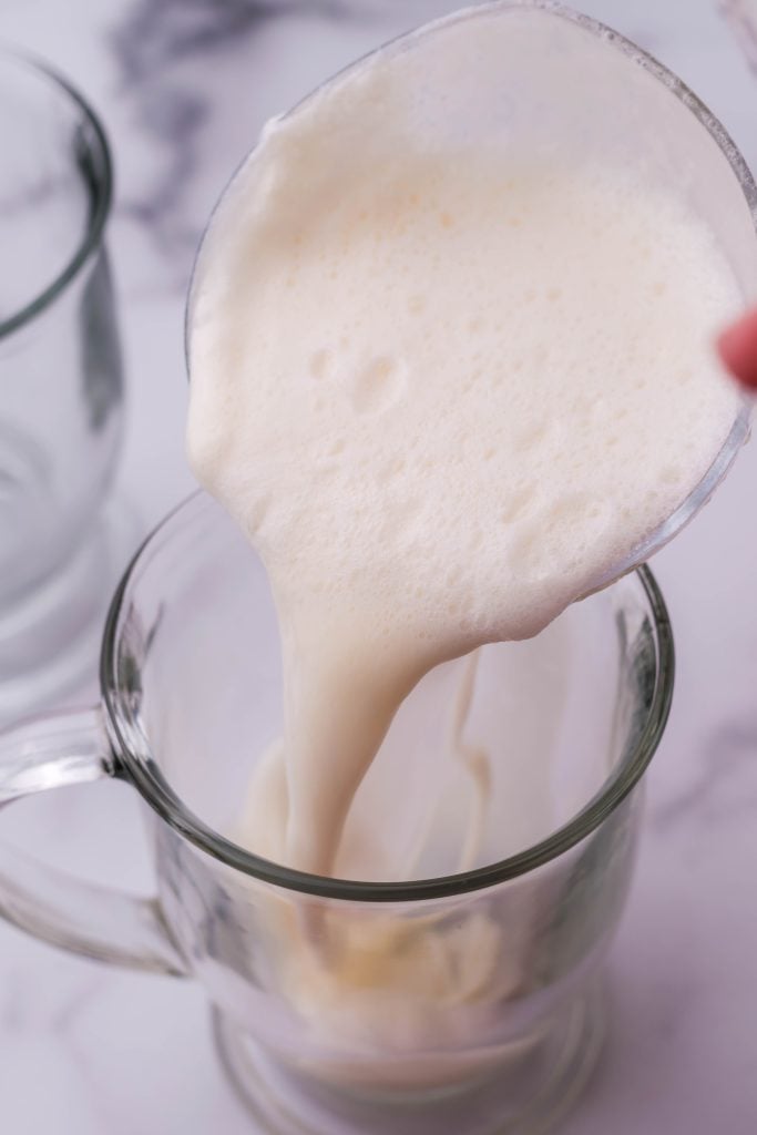creamy white christmas punch being ladled into a glass mug