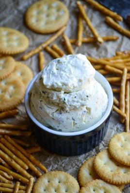 homemade boursin cheese served in a blue ramekin with crackers and pretzels on the side