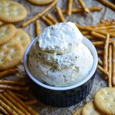 homemade boursin cheese served in a blue ramekin with crackers and pretzels on the side