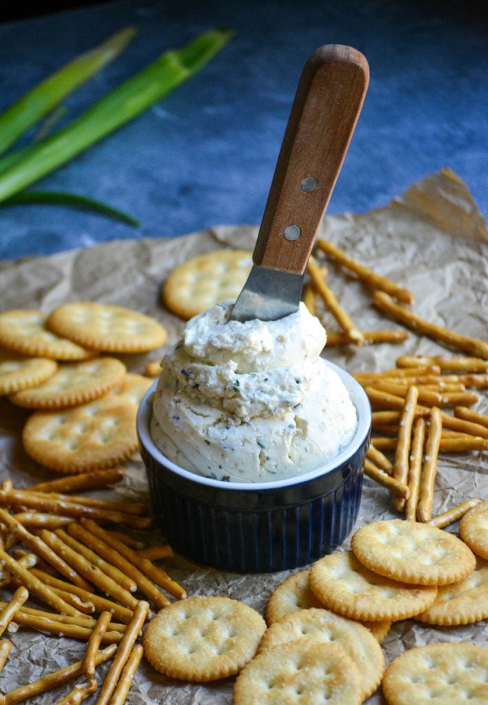 homemade boursin cheese in a blue ramekin with a small wooden spreader stuck in the top of the cheese