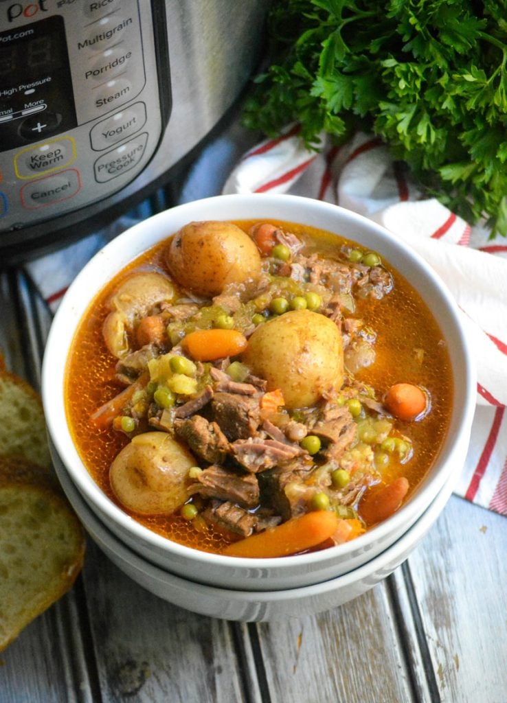 instant pot beef stew served in a white bowl with a pressure cooker shown in the background