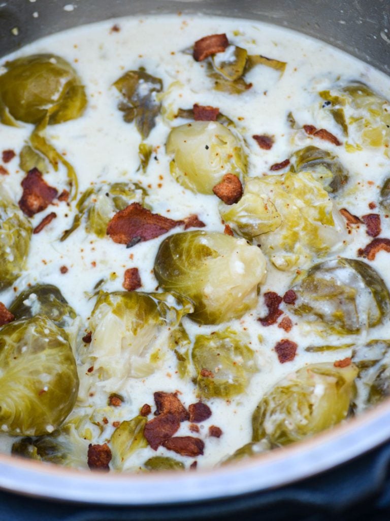 Instant Pot creamed brussels sprouts with bacon shown in the pot in a thick cream sauce