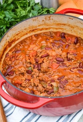 cheeseburger chili shown in a red dutch oven with a wooden spoon for serving