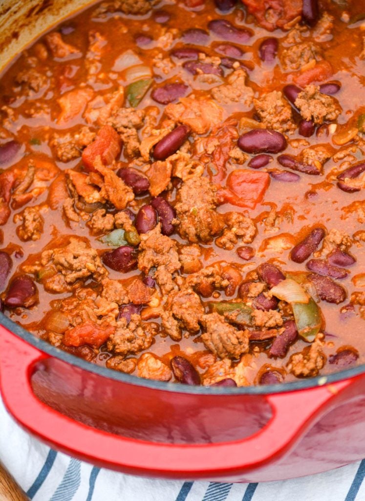 cheeseburger chili shown in a red dutch oven with a wooden spoon for serving